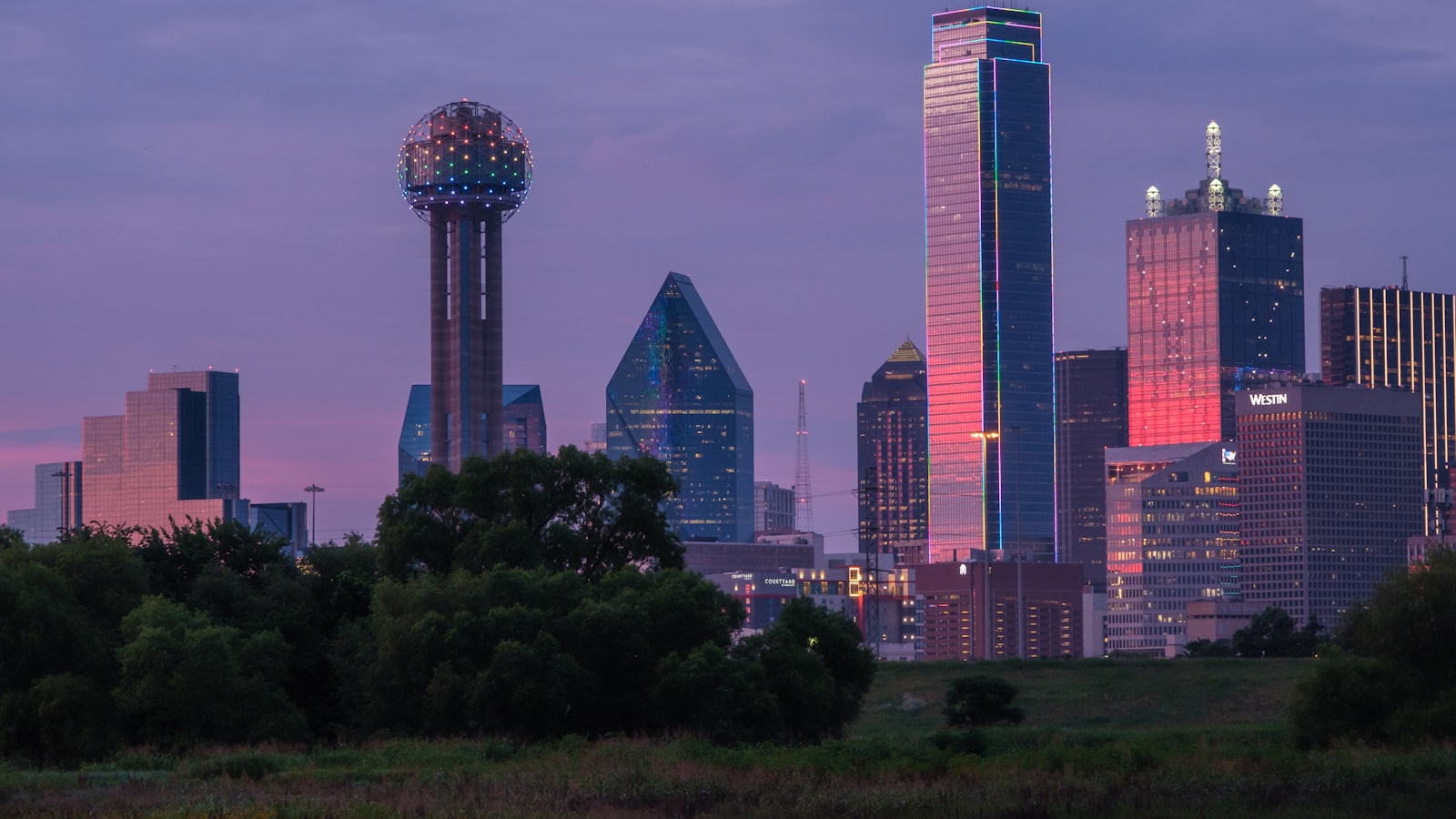 Texas city skyline at dusk with high-voltage transmission lines, representing the deregulated commercial electricity market.